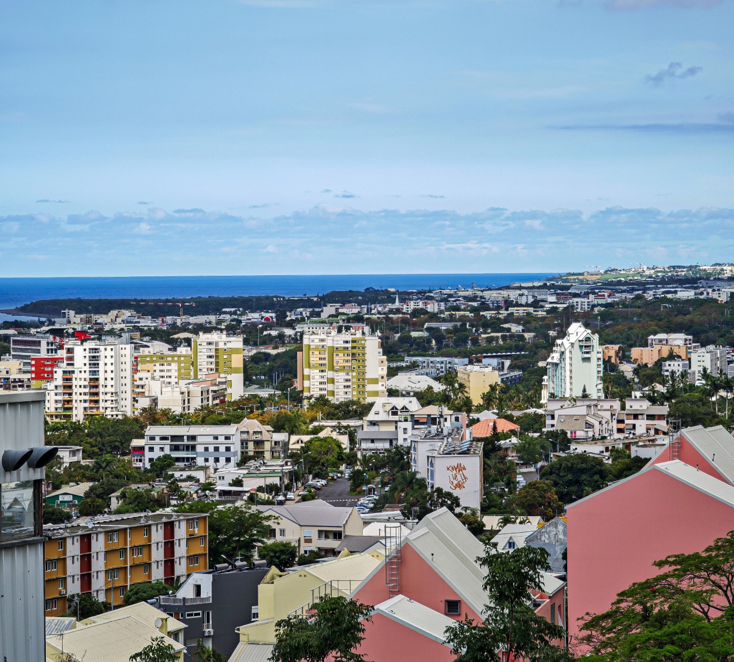 Vue panoramique d'une ville de La Réunion avec ses immeubles résidentiels et l'océan Indien en arrière-plan