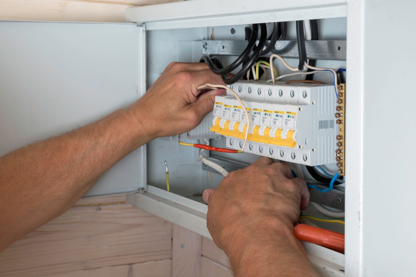 Électricien vérifiant les disjoncteurs d'un tableau électrique lors d'un diagnostic électricité